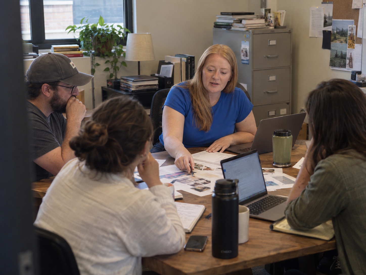 A cross-functional team coordinating shared materials around a table